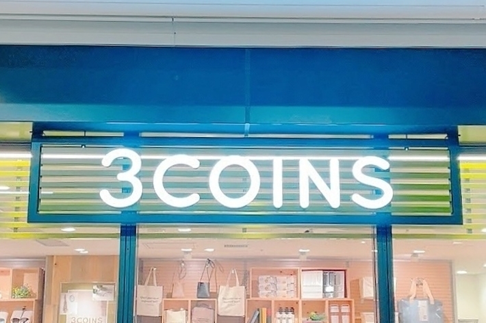 3COINSの店頭看板。店舗内にはバッグや雑貨が陳列されている。