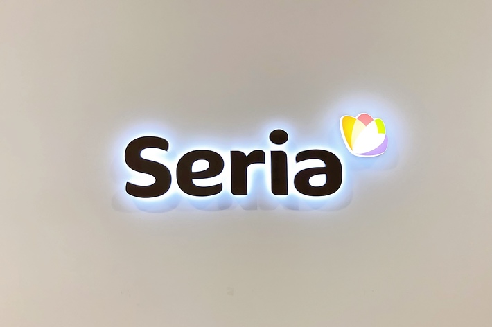 Seriaのロゴマーク。白い背景に「Seria」という黒い文字が中心にあり、右上にはカラフルな花のデザインがある。