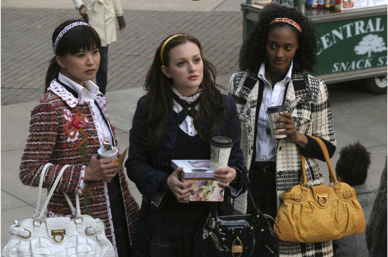 Jessica Szohr, Leighton Meester, and Nicole Fiscella are standing outdoors, holding coffee cups and bags, dressed in preppy, stylish outfits with headbands