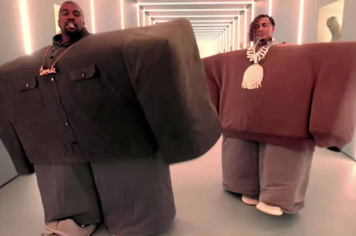 Kanye West and Lil Pump wearing oversized, blocky outfits, walking down a futuristic, LED-lit hallway. Kanye wears a 'Yeezus' necklace