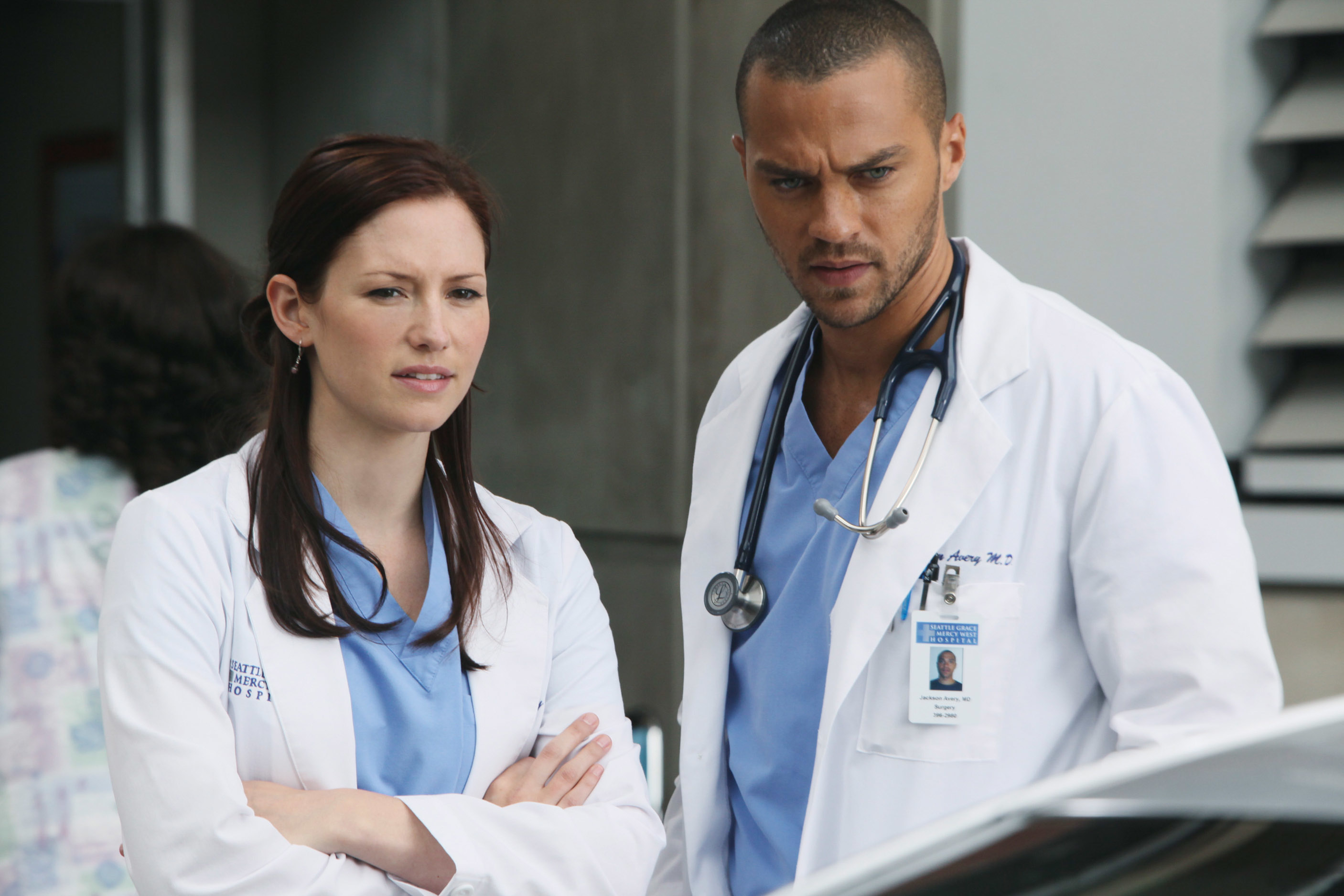Lexie Grey and Jackson Avery, characters from Grey's Anatomy, stand together in hospital attire with serious expressions