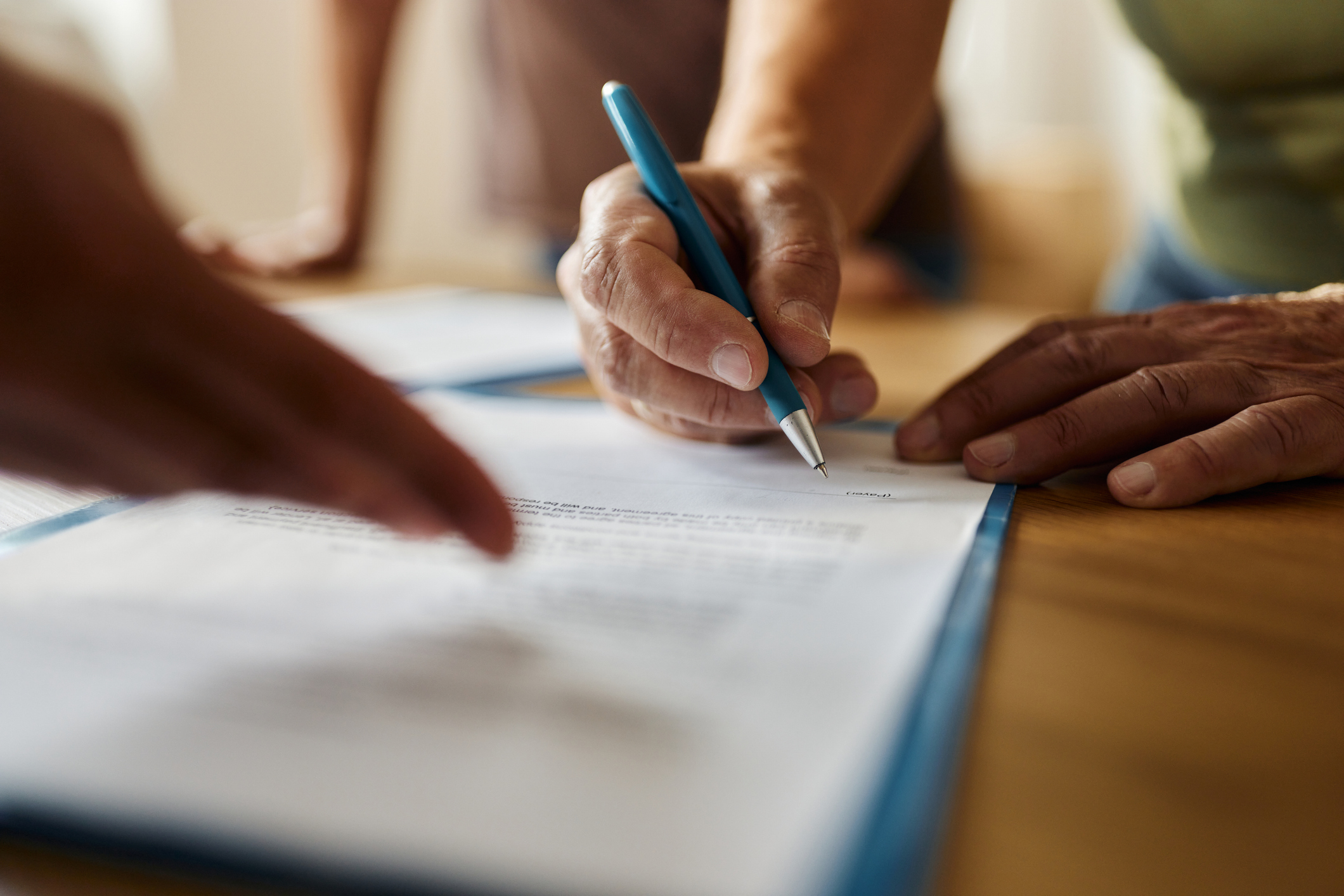 Hands of two people signing a document on a clipboard
