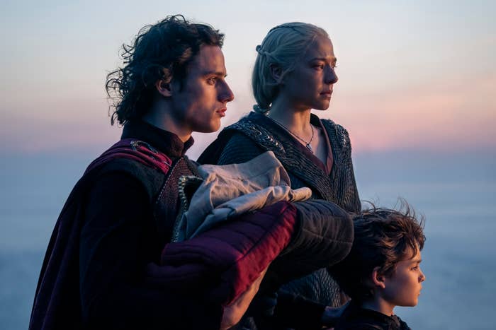 Emma D’Arcy and others dressed in medieval attire looking pensively into the distance