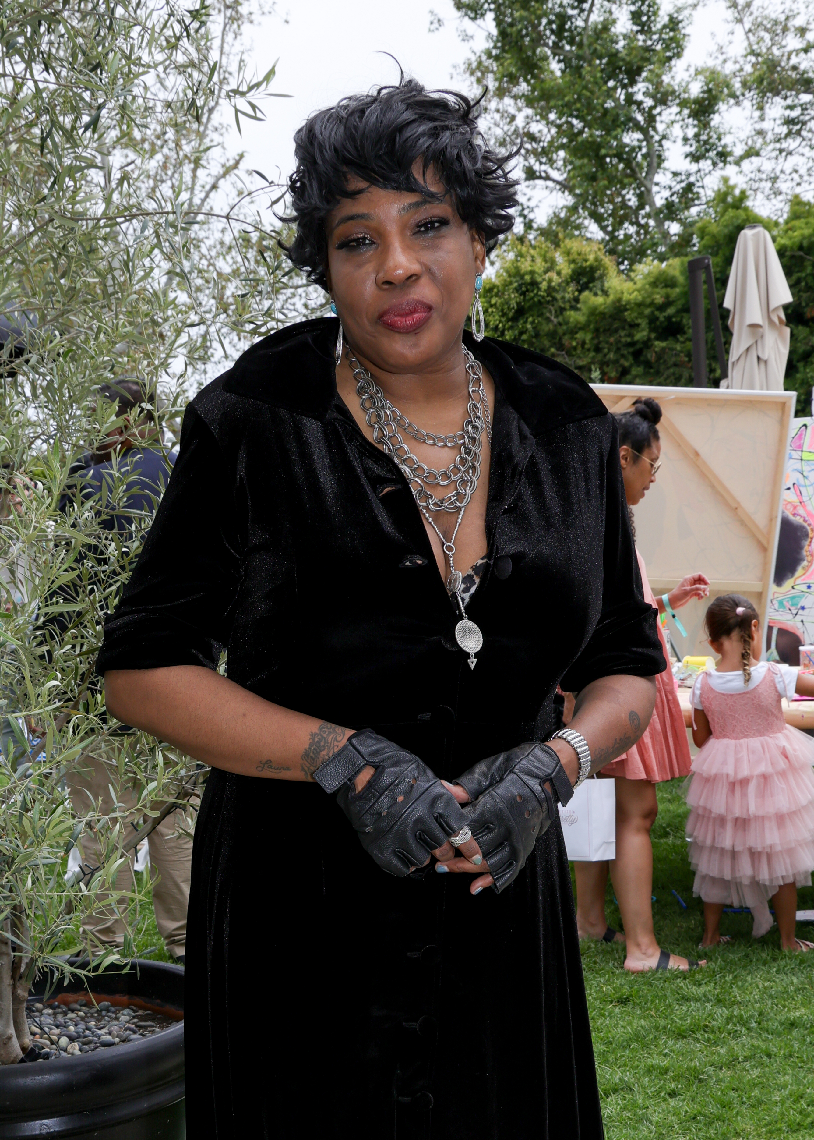 Macy Gray attends outdoor event in a velvet dress with layered necklaces and fingerless gloves