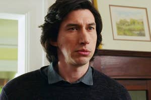 Adam Driver stands indoors from "Marriage Story", wearing a dark sweater over a collared shirt, looking serious and thoughtful