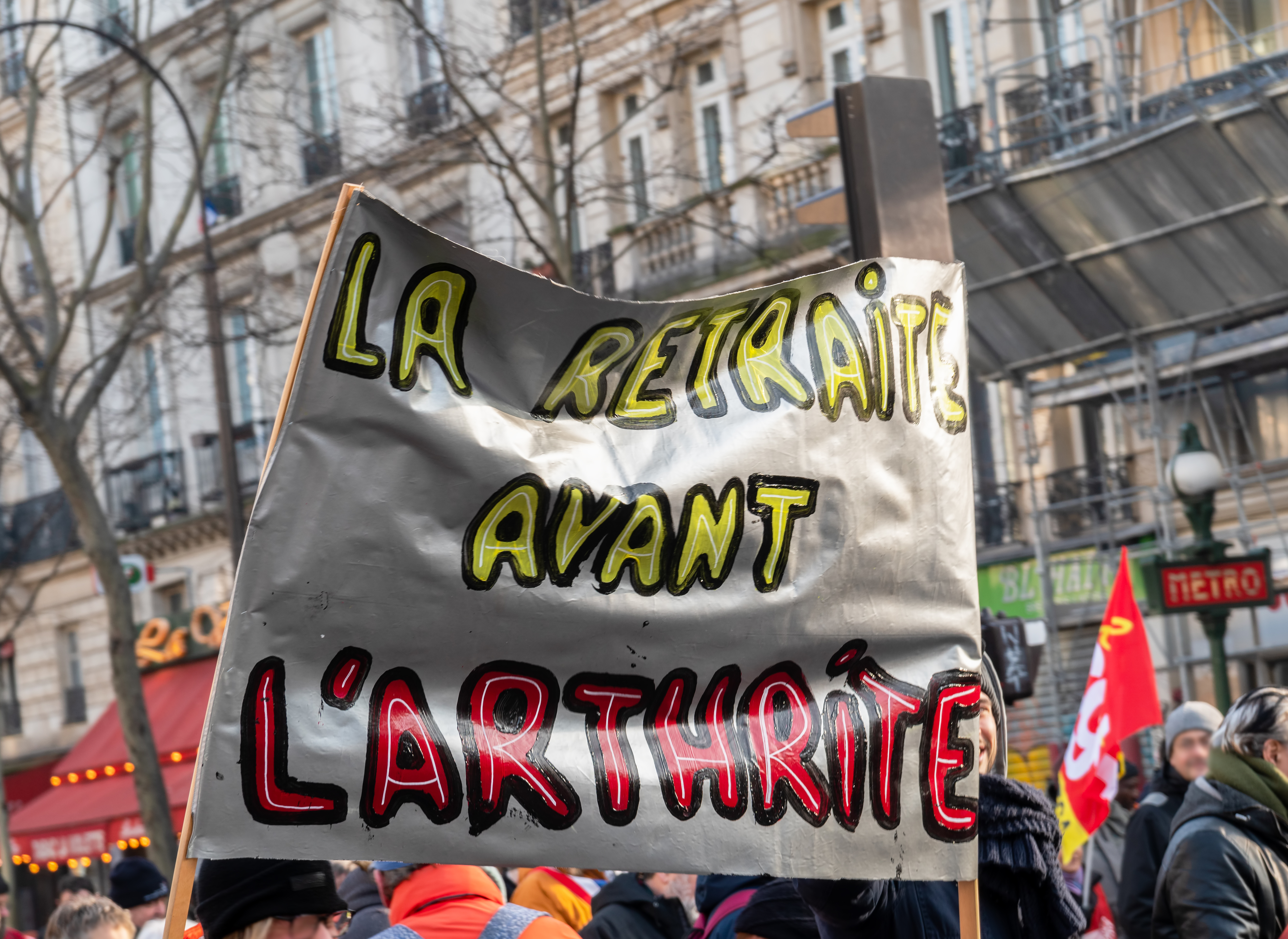 Protesters hold a sign that reads "La retraite avant l'arthrite" during a street demonstration.