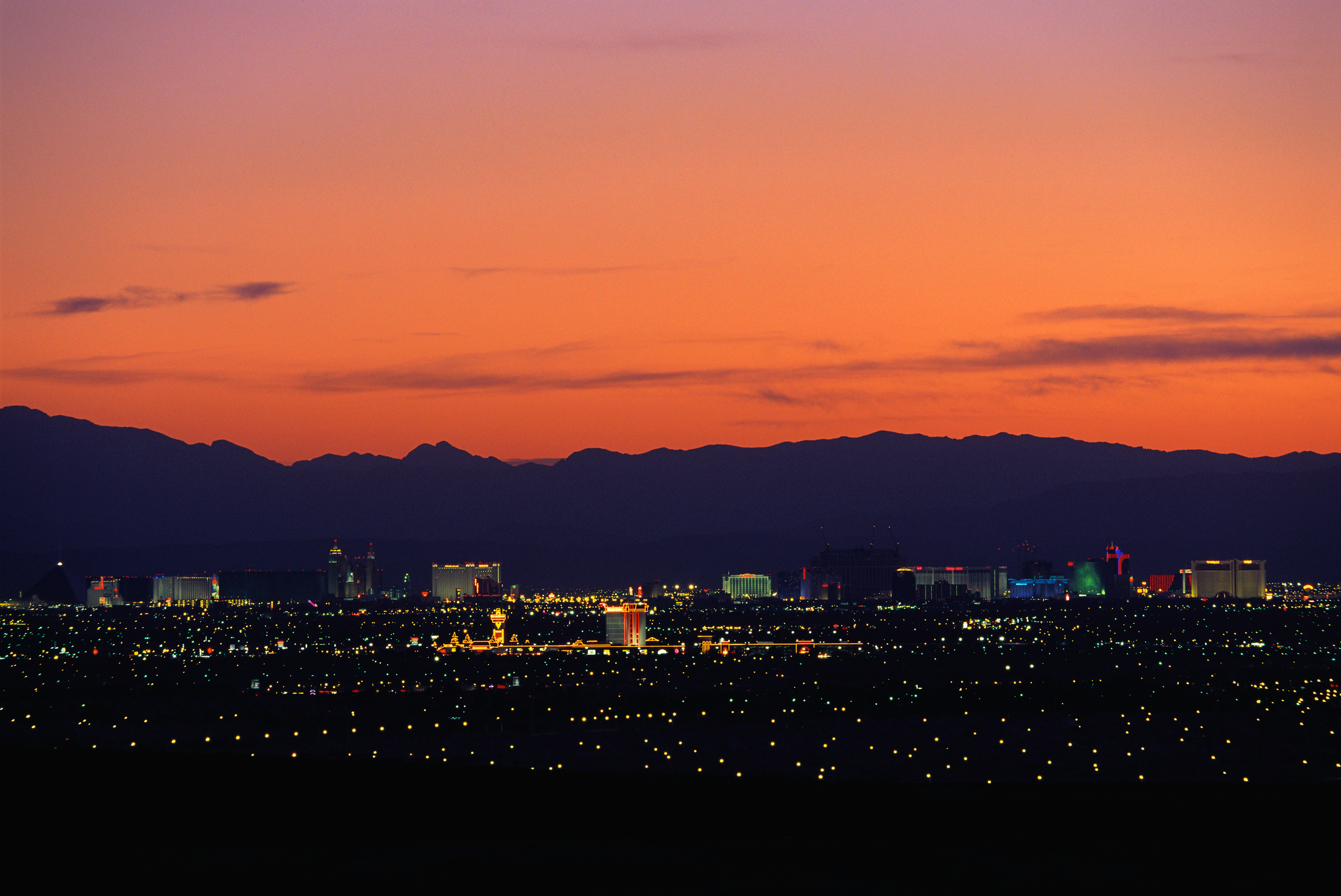 Distant view of Las Vegas city skyline at sunset, with mountains in the background and city lights starting to illuminate