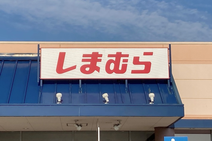 An exterior of a storefront with a sign in Japanese characters. The storefront has a ramp and accessible parking space