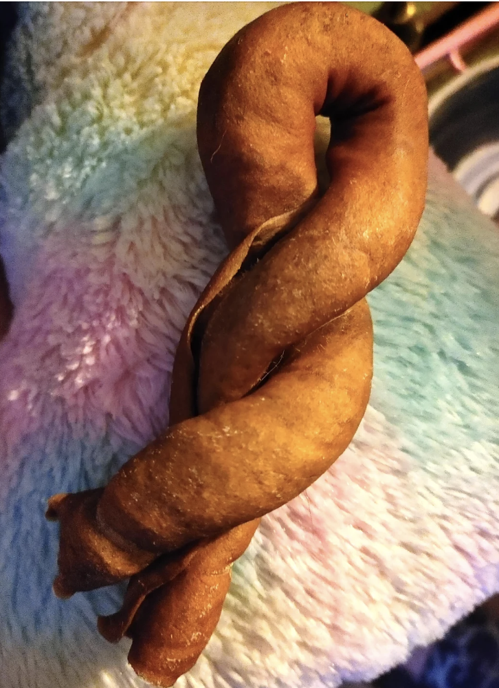 A twisted dog chew treat placed on a fluffy, multicolored blanket