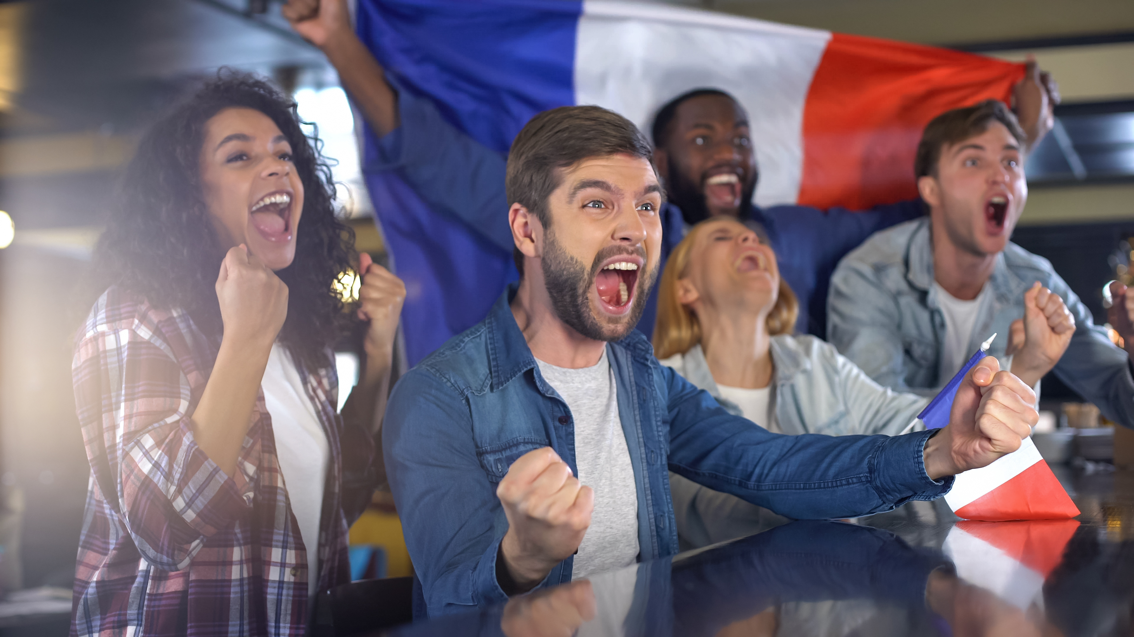 People enthusiastically cheering while holding a French flag