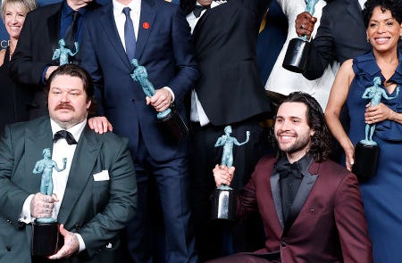 Cast of &quot;Stranger Things&quot; at the SAG Awards proudly hold their awards. Several cast members dress in formal attire, with some in suits and others in gowns