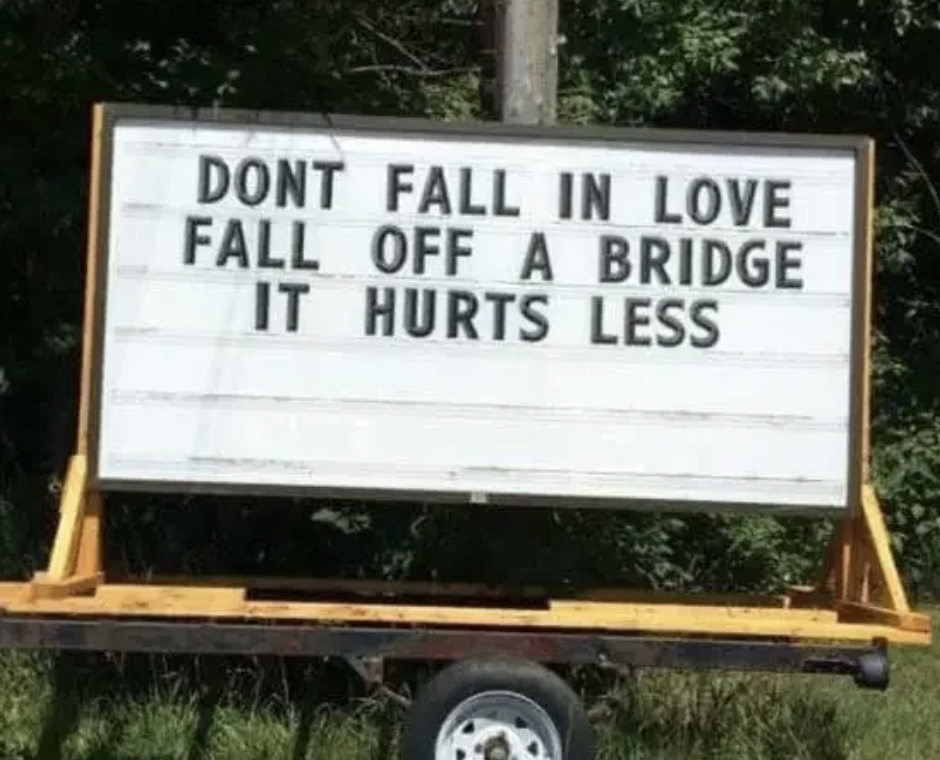 Signboard reads: &quot;DON&#x27;T FALL IN LOVE FALL OFF A BRIDGE IT HURTS LESS.&quot;