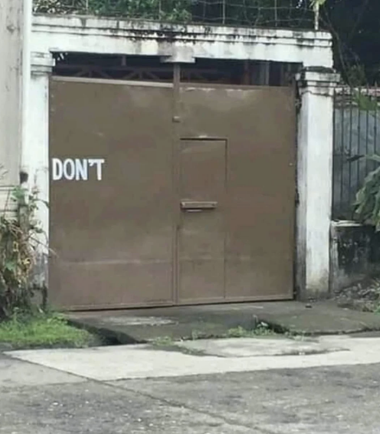 A large, closed metal gate with &quot;DON&#x27;T&quot; painted in white on the left side