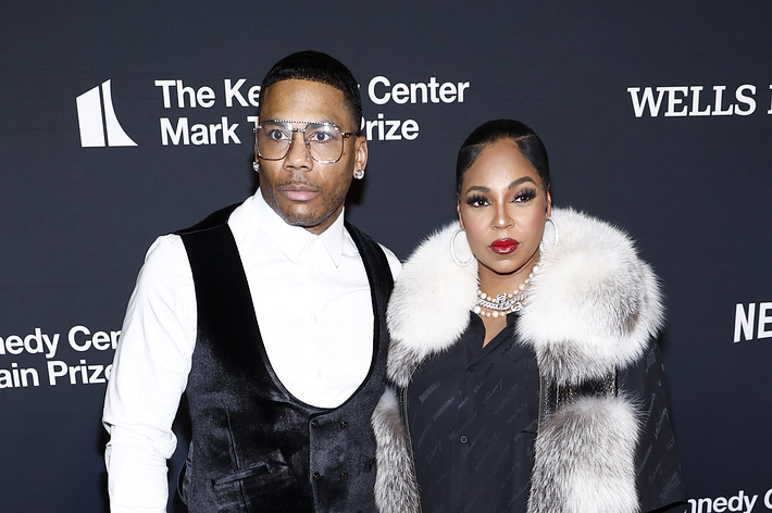 Nelly in a velvet suit with a white shirt and Ashanti in a fur coat over a black outfit at the Kennedy Center Mark Twain Prize event red carpet