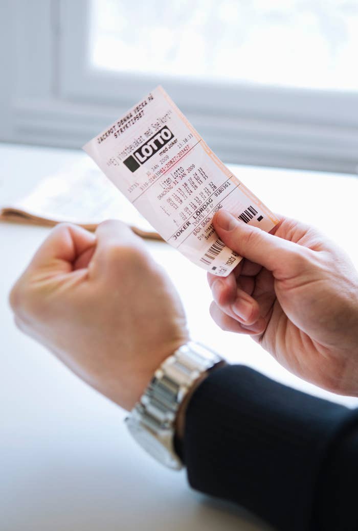 A person is holding a lottery ticket in one hand and making a fist with the other, suggesting excitement or anticipation