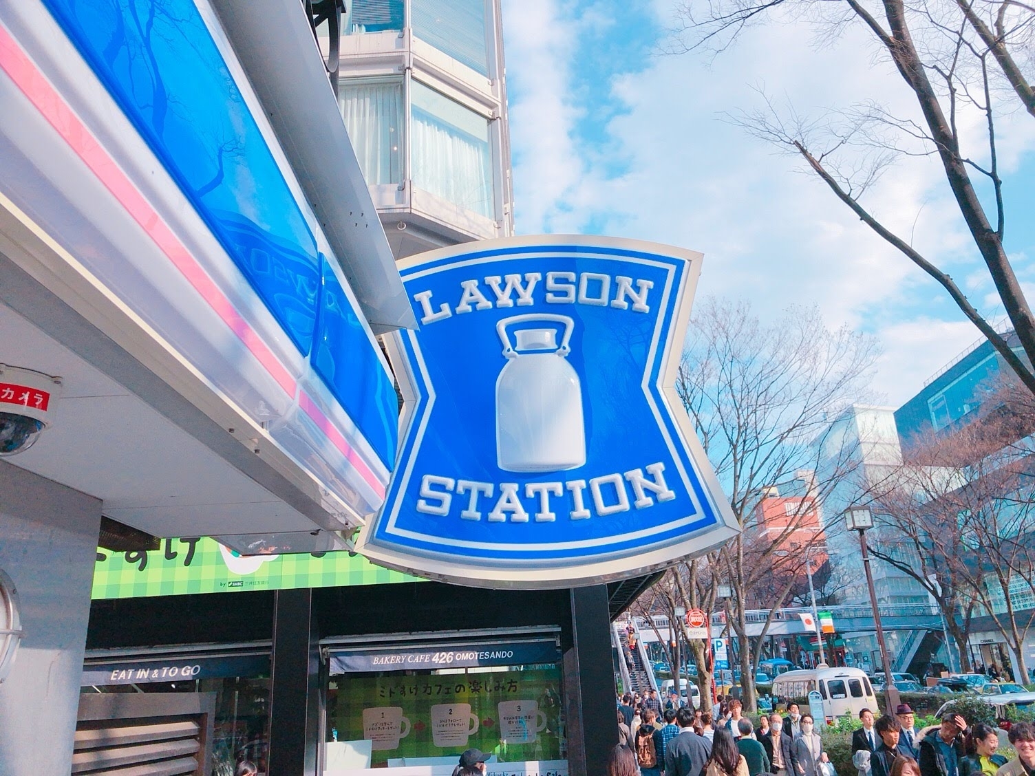 ローソンの看板が見える外の景色。多くの人が周囲を歩いている。