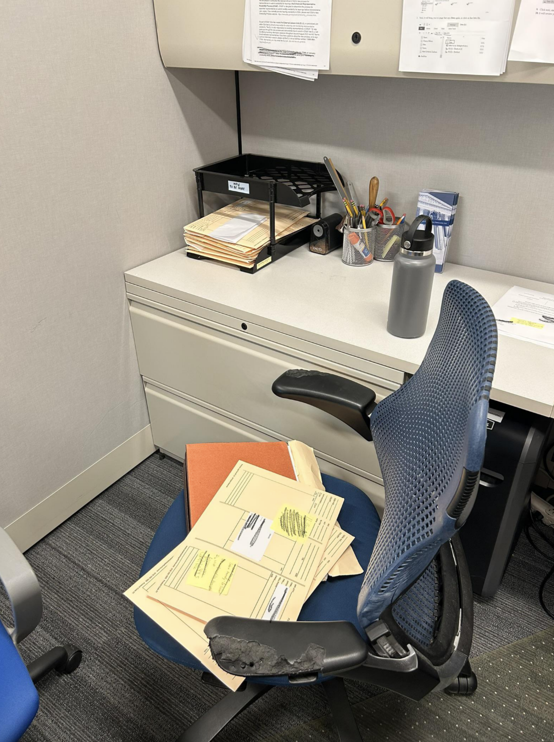 Piles of paperwork on an office chair, which is next to organized an desk