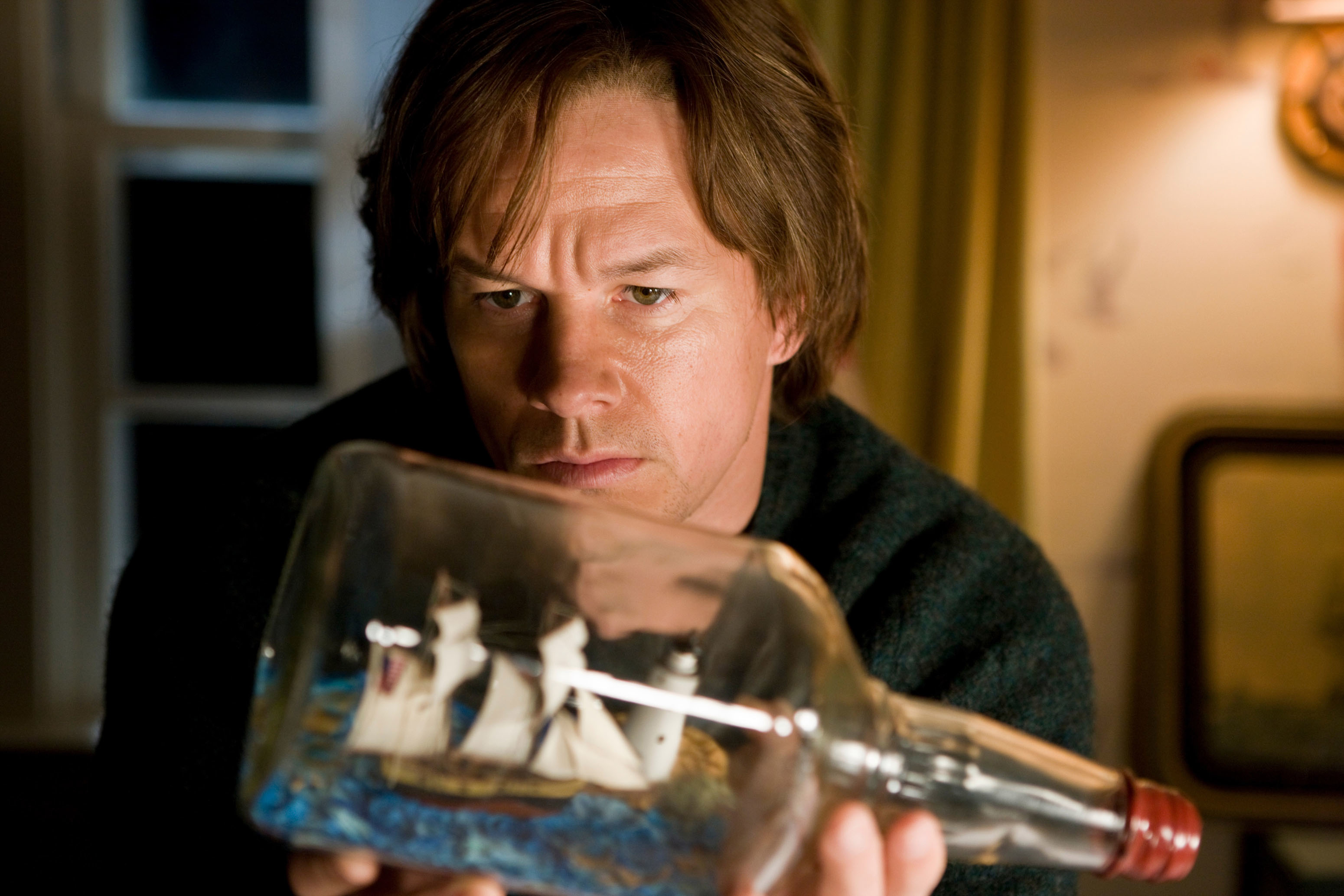 Mark Wahlberg intensely examines a ship in a bottle in a movie scene