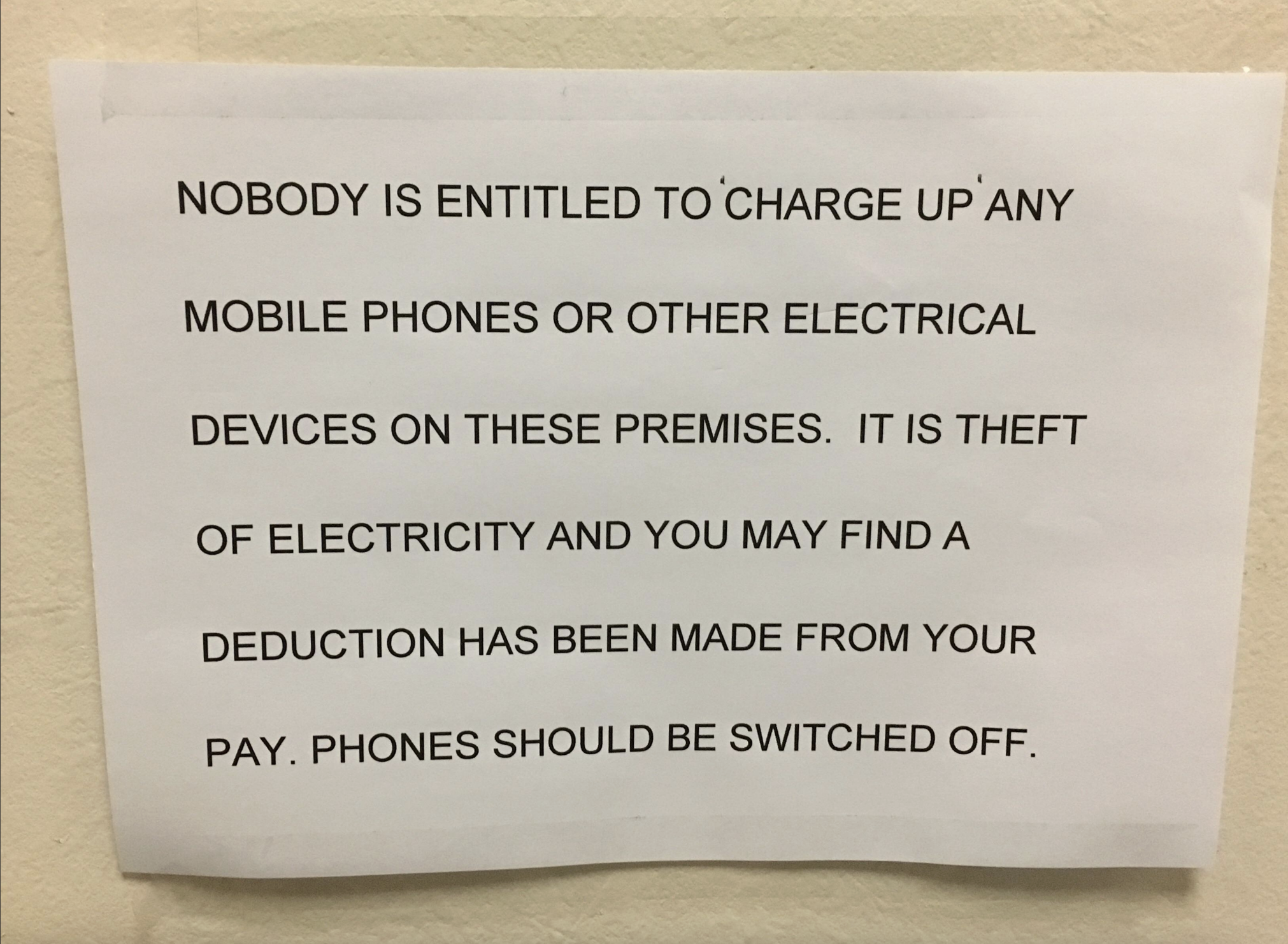 Sign stating: "Nobody is entitled to 'charge up' any mobile phones or other electrical devices on these premises. It is theft of electricity and you may find a deduction has been made from your pay. Phones should be switched off."