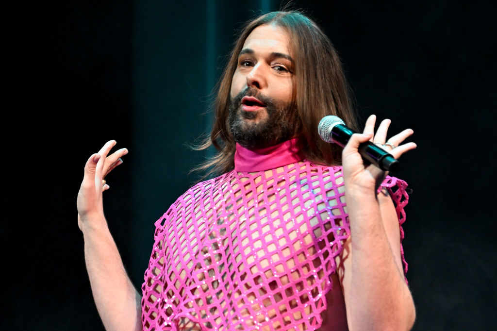 Jonathan Van Ness speaking into a microphone, wearing a mesh top