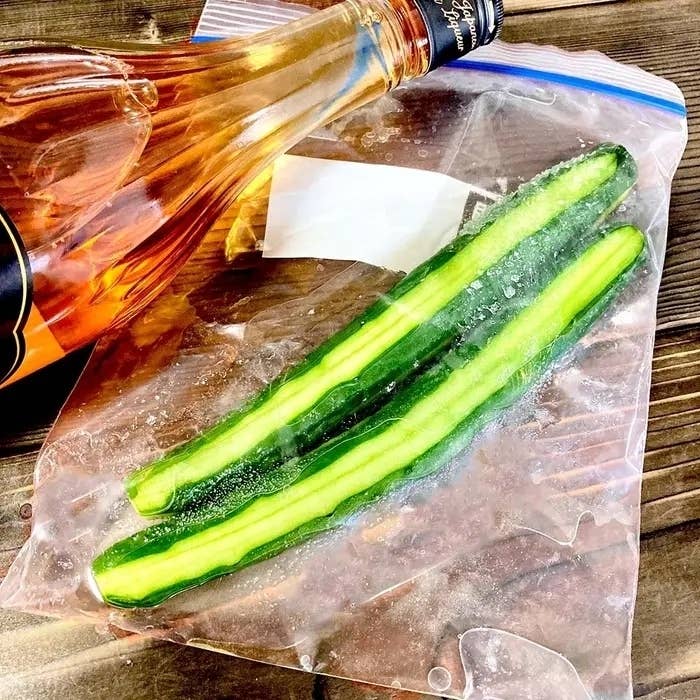 キュウリがスライスされた状態でジップロックに2本入っています。隣に梅酒のボトルが倒れています。