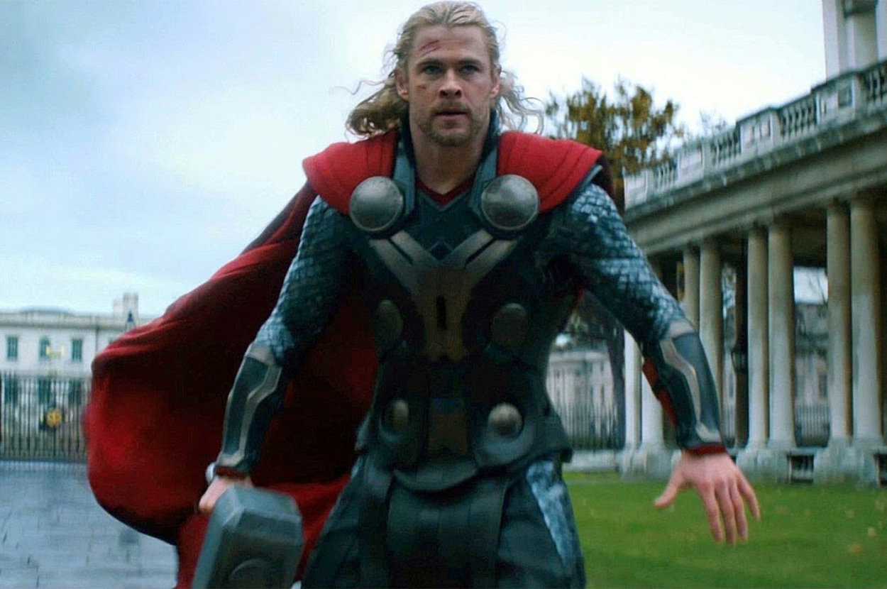 Chris Hemsworth as Thor, wearing traditional Asgardian armor with a red cape, holds his hammer Mjölnir in an outdoor setting with classical architecture