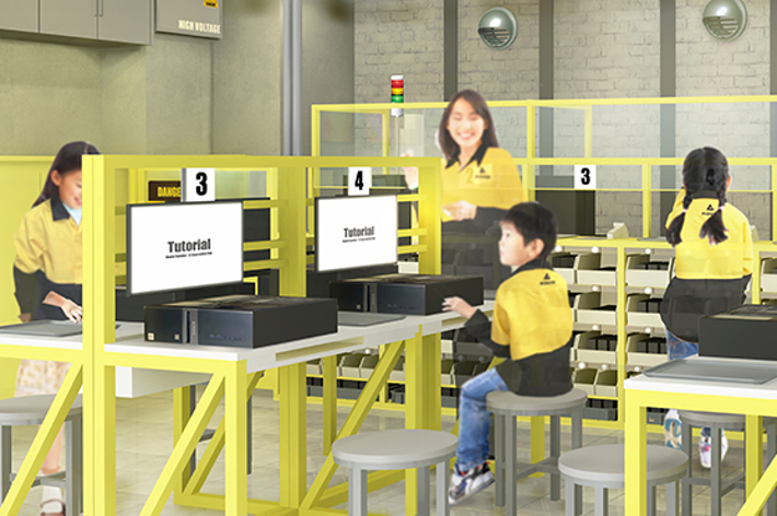 子供たちが数台のコンピュータで勉強している室内の光景。子供たちは黄色いユニフォームを着用しています。