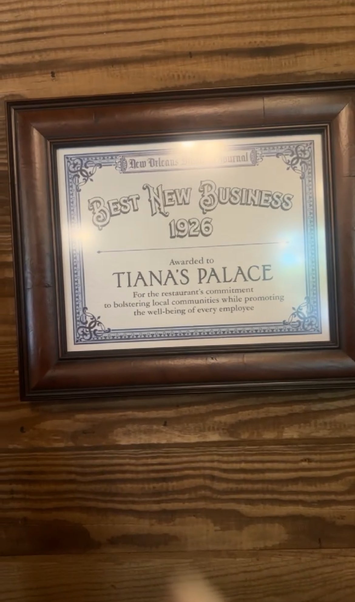 A framed certificate awarded to Tiana&#x27;s Foods for &quot;Best New Business 1926,&quot; recognizing the restaurant&#x27;s commitment to local community and employee well-being
