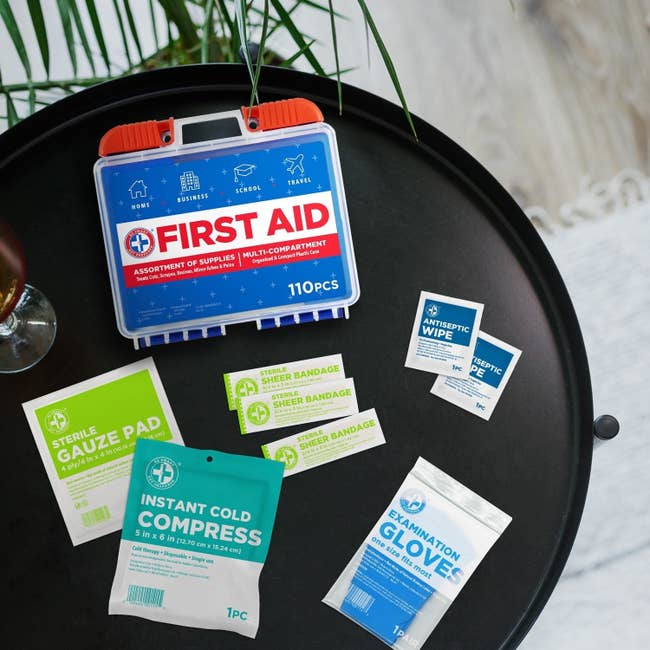First assistance  kit with 110 pieces connected  a achromatic  table, including gauze pads, an instant acold  compress, bandages, antiseptic wipes, and introspection  gloves