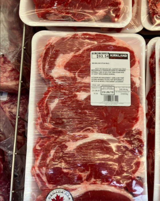 Package of Kirkland ribeye steak priced at $93.54, showing three large cuts of meat under plastic wrap. Canadian AAA grade, weight and barcode visible