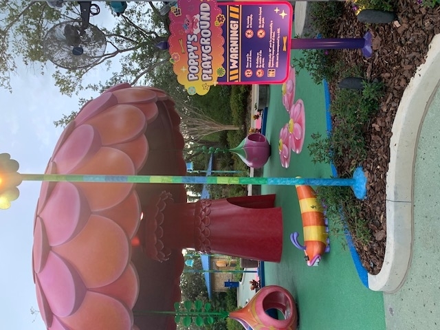 Poppy's Playground features a colorful, whimsical mushroom structure with playful activity areas and a warning sign with safety alerts for children