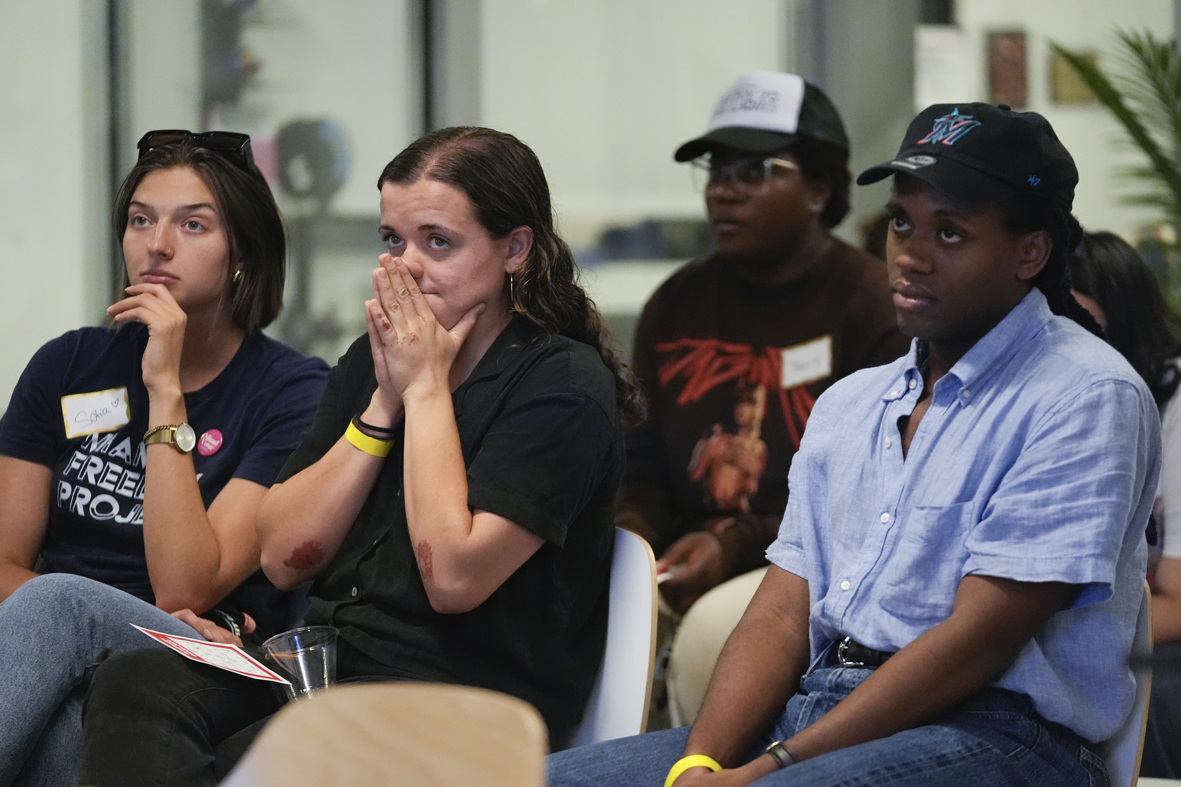 A group of people sitting in a room, looking focused and emotional. They appear to be listening intently to something