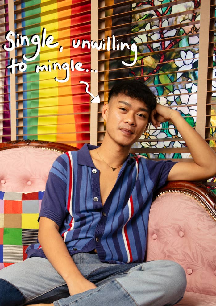 A person sits on a patterned couch with a rainbow flag in the background, wearing a striped shirt. Handwritten text reads, "Single, unwilling to mingle…"