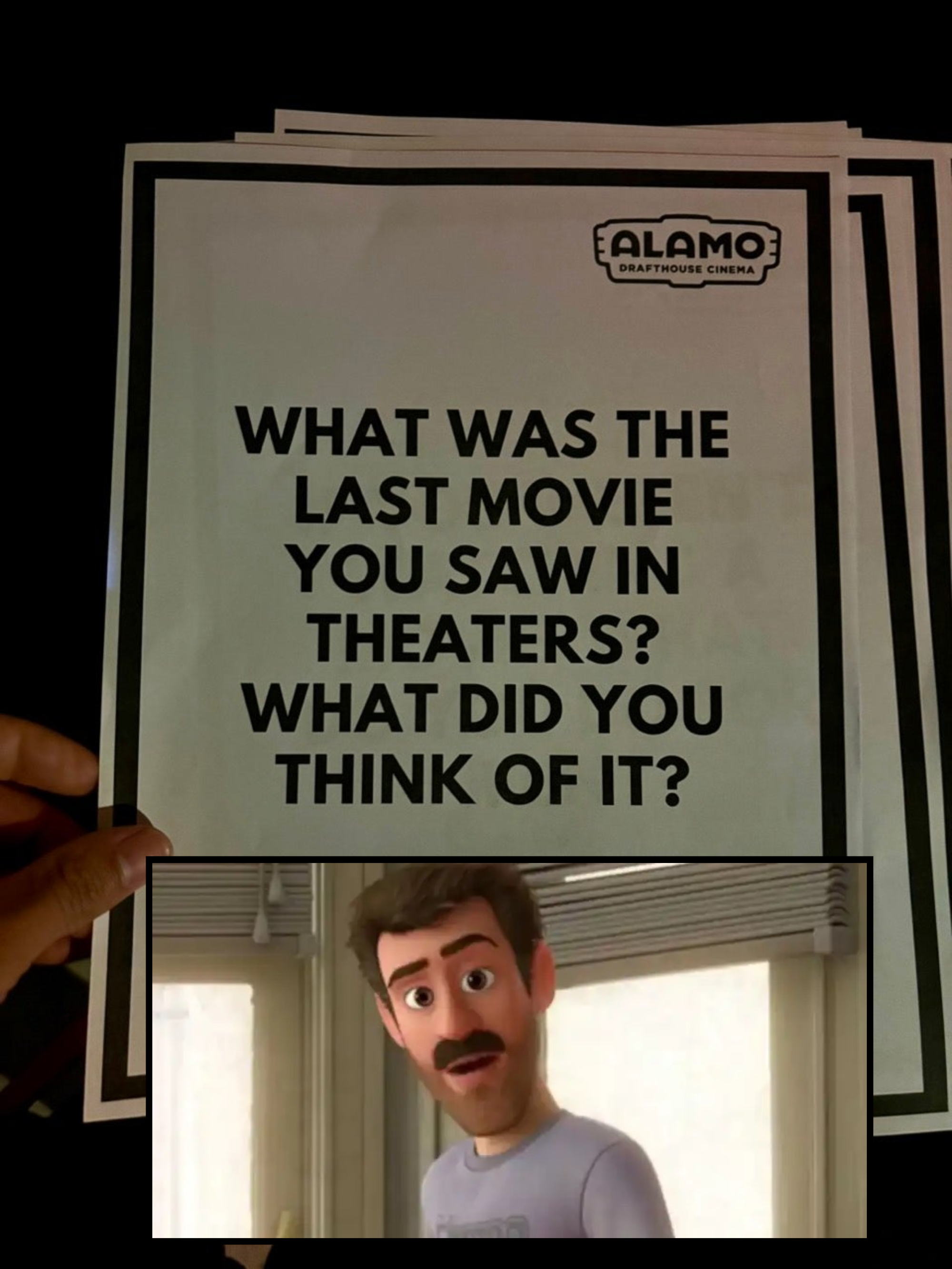 A hand holds a sign from Alamo Drafthouse Cinema that reads, "What was the last movie you saw in theaters? What did you think of it?"