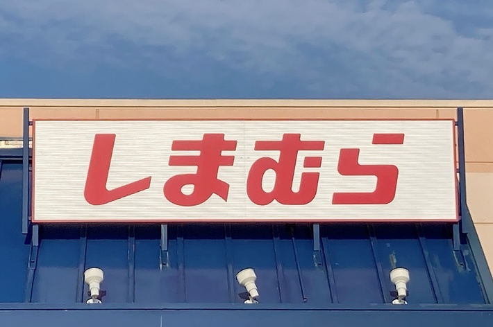 The image shows the exterior of a store with a sign above it displaying Japanese characters. There is also a handicapped parking sign visible