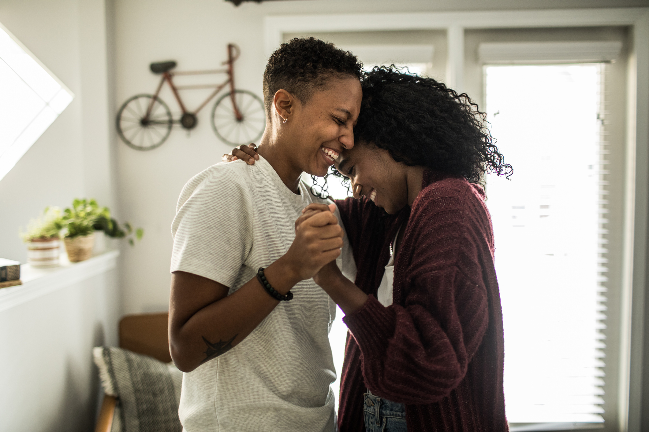 Two people embrace and smile in a cozy room with a bicycle decor on the wall