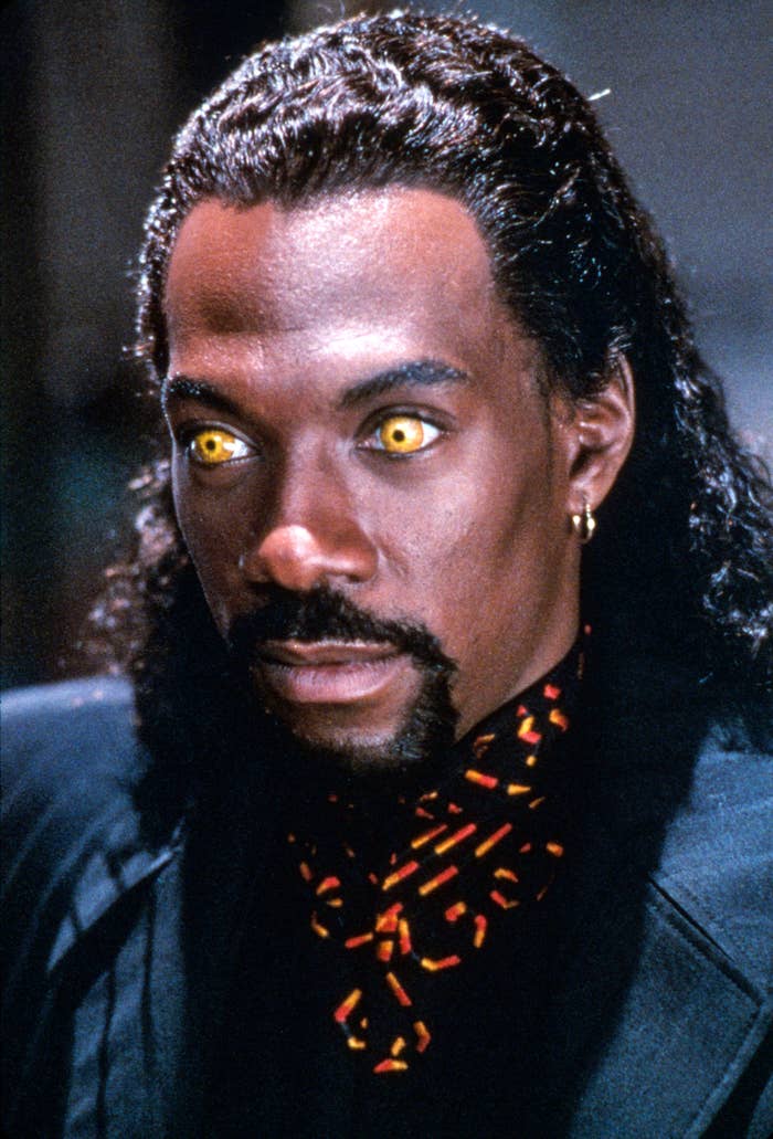 Eddie Murphy successful  quality  with glowing yellowish  eyes and dressed successful  a acheronian  suit, accessorized with a patterned scarf