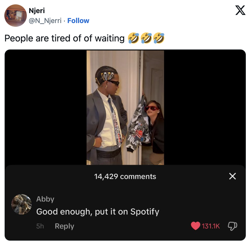 Njeri tweets a photo with two people posing; one holds a blazer with a graphic design. Abby’s comment says, “Good enough, put it on Spotify.” Image has 14,429 comments