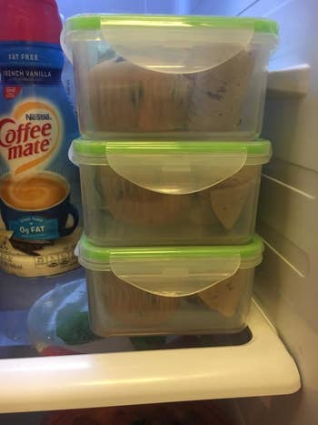 reviewer's three plastic containers stacked in a fridge, each containing muffins. Coffee-mate creamer and other grocery items are visible beside the containers