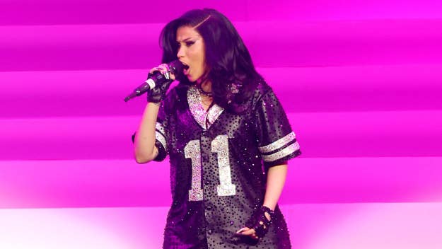 Cardi B wearing a sequined jersey with the number 11 performs onstage with a microphone