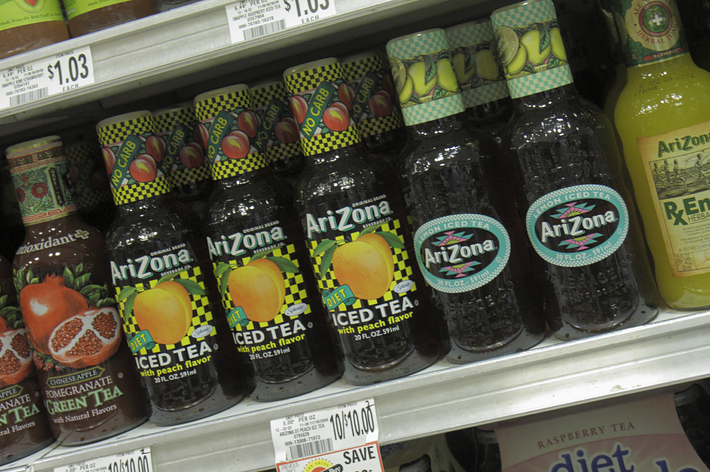 Bottles of Snapple and Arizona iced tea on grocery store shelves with price tags of $1.03 each