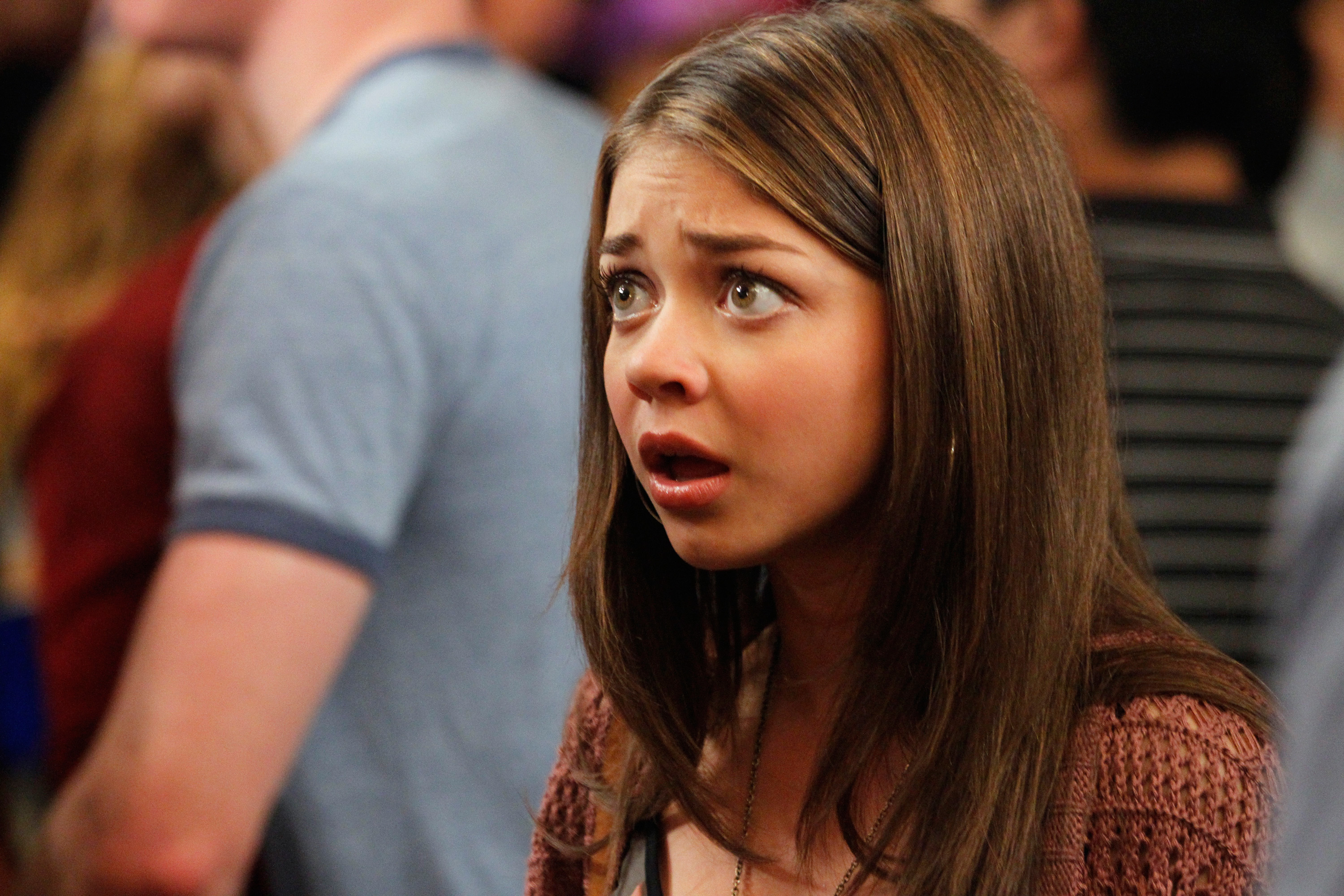 Sarah Hyland is shown with an anxious expression, wearing a casual outfit amidst a crowd