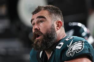Jason Kelce, football player for the Philadelphia Eagles, shown during a game with a helmet off, wearing a team jersey, and looking to the side with an open mouth