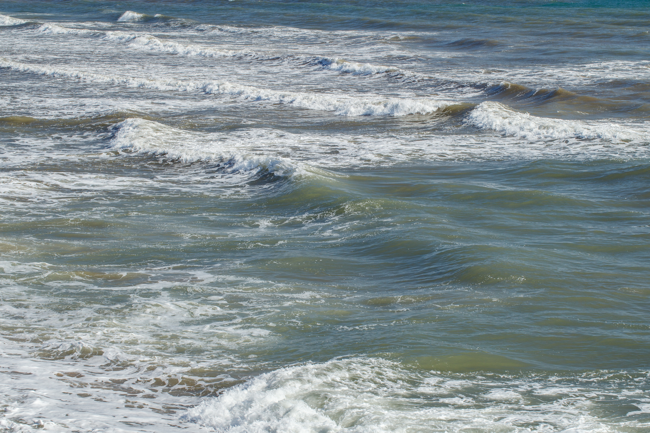 Waves gently crash on a serene, open sea. No people are visible in the image