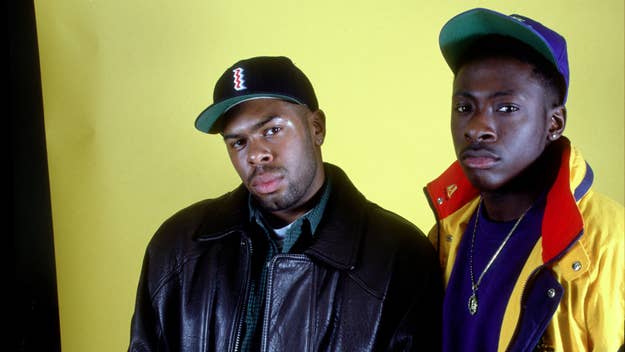 Pete Rock and C.L. Smooth pose against a yellow background. Pete Rock wears a leather jacket and cap, while C.L. Smooth wears a colorful jacket and cap
