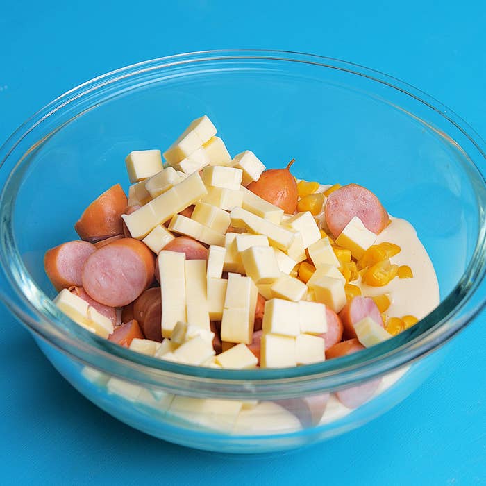 ガラスボウルに角切りのチーズ、スライスしたソーセージ、コーンが入っています。