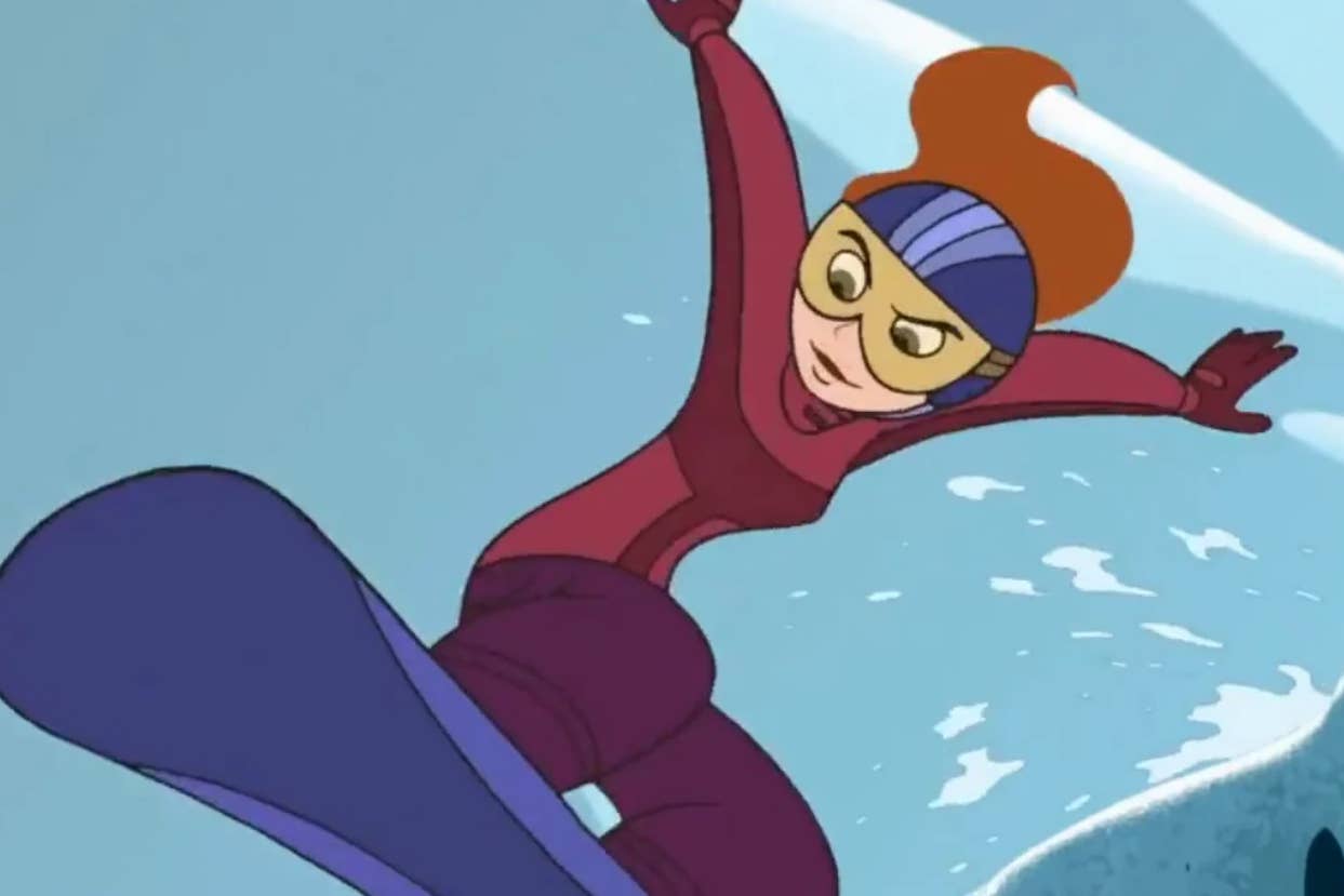 Animated character Kim Possible is snowboarding down a slope, wearing protective goggles and winter sports attire