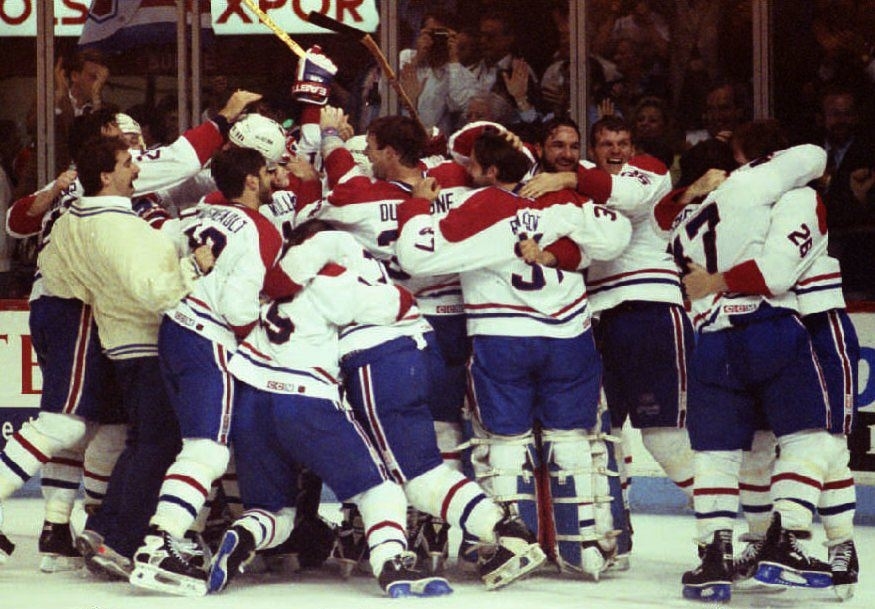 Group of Montreal Canadiens hockey players celebrate a victory on the ice, embracing and cheering