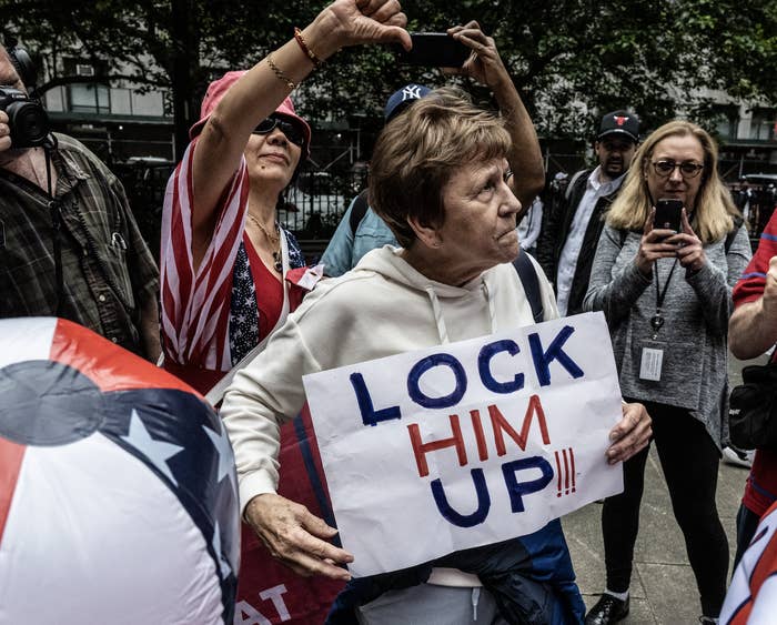 A woman holding a sign that says, &quot;Lock Him Up!!!&quot;