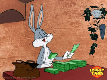 Bugs Bunny is sitting at a table, counting a large stash of money. A travel bag filled with more money is beside him. The scene is from Looney Tunes